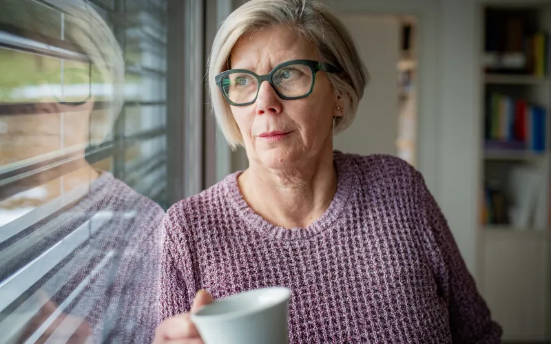 vrouw kijkt uit raam naar balkon