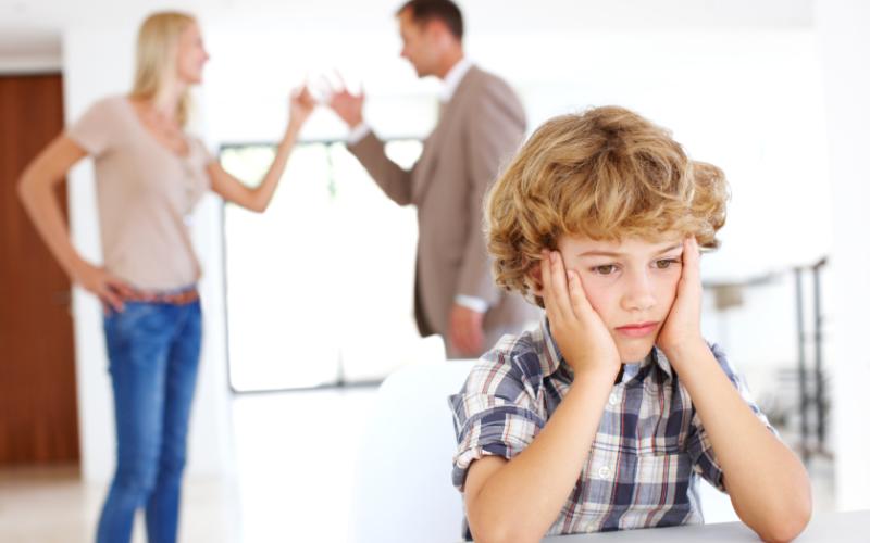 Foto van ouders met ruzie en sip kijkend kind