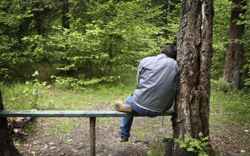 Man op bankje in de natuur