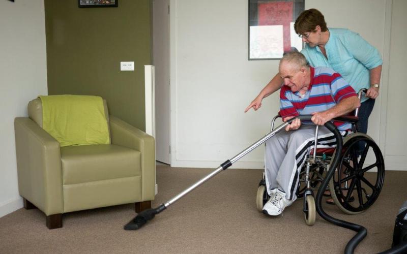 man in rolstoel met huishoudelijke hulp