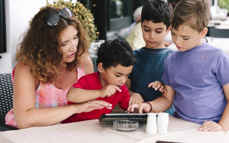 moeder met drie zoons kijken op de tablet