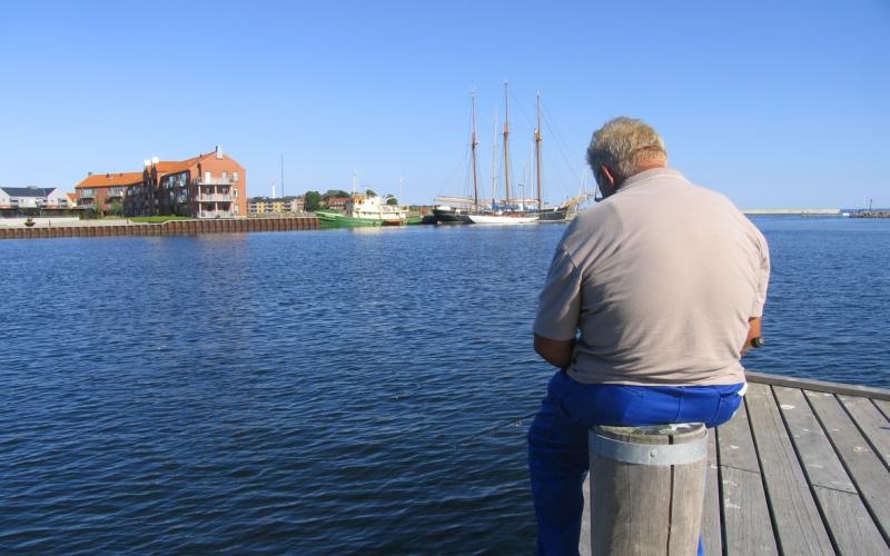 Man zit op een paal aan het water Man zit op een paal aan het water