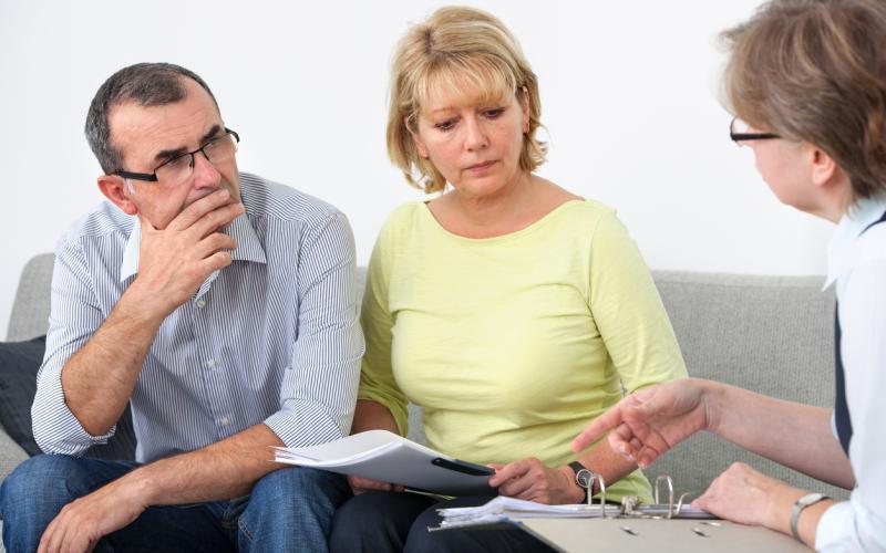 Man en vrouw, zittend op de bank, in gesprek met een man Man en vrouw, zittend op de bank, in gesprek met een man