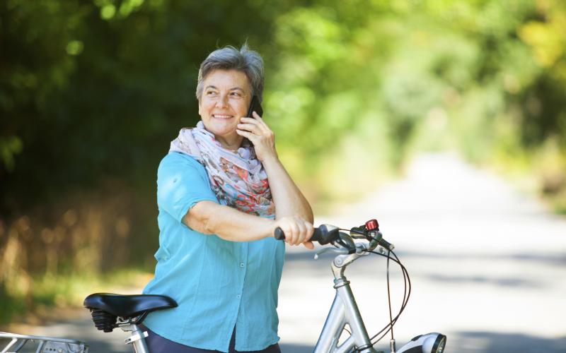 Vrouw staat al bellend naast haar fiets