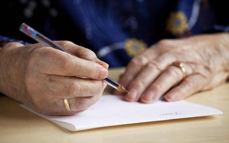 Handen van een ouder iemand die een brief schrijft Handen van een ouder iemand die een brief schrijft