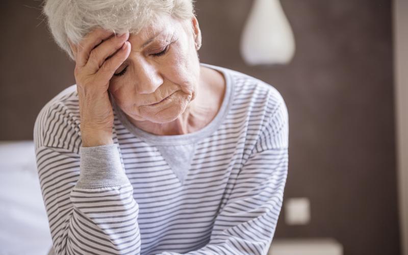 Foto van een vrouw met haar ogen dicht en haar hand tegen haar voorhoofd