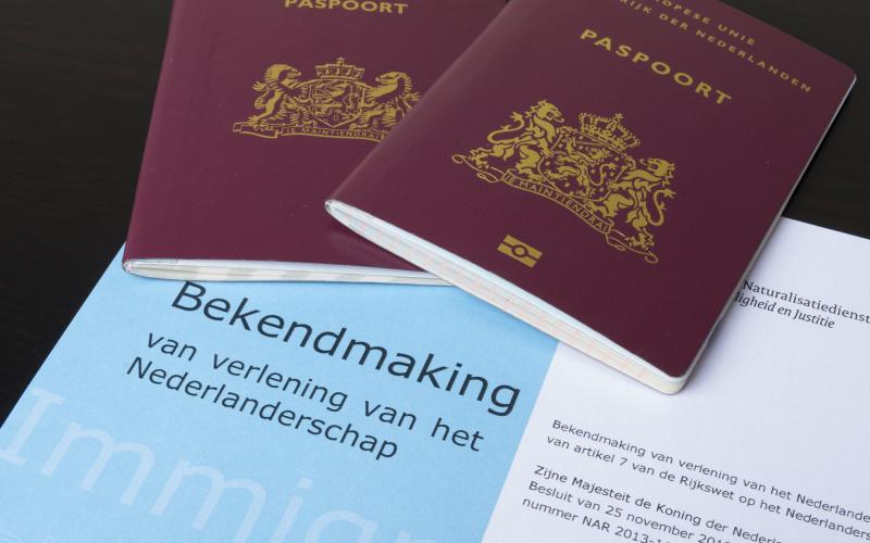 Twee Nederlandse paspoorten en daaronder een formulier met de bekendmaking voor verlenging van het Nederlanderschap