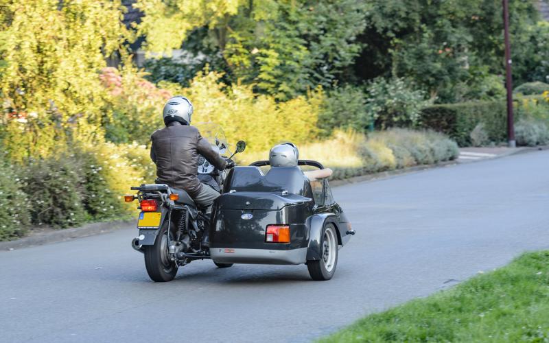 Een veteraan zit in een zijspan van een rijdende motor