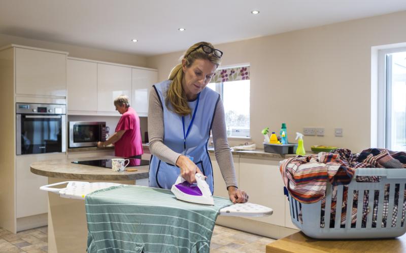 Vrouw strijkt bij oudere dame thuis Vrouw strijkt bij oudere dame thuis
