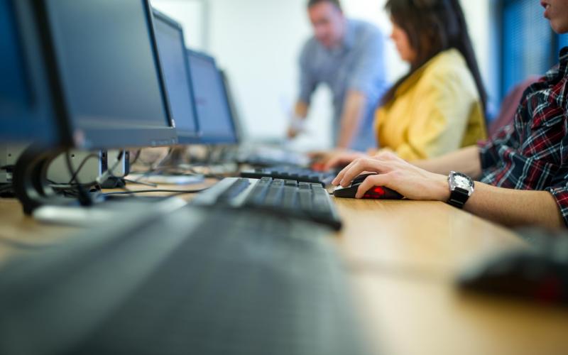 Mensen achter een computer, vrouw heeft geel shirt aan Mensen achter een computer, vrouw heeft geel shirt aan