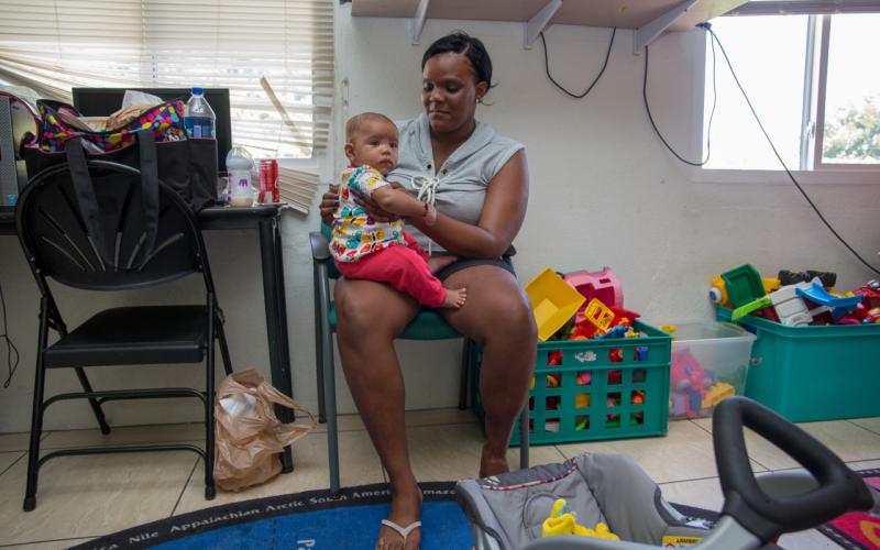 Een Caribische vrouw houdt een klein kind vast op haar schoot