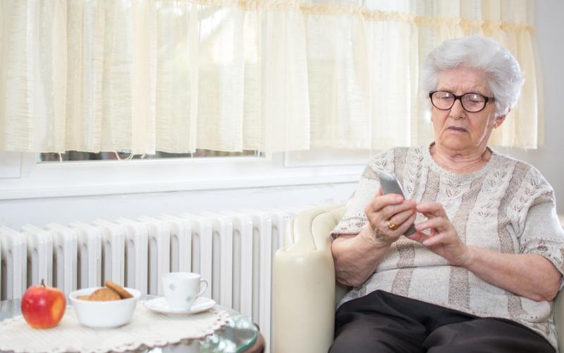 Bejaarde vrouw met telefoon in haar hand