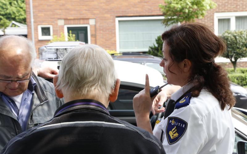Politieagente spreekt een oude man toe voor de deur tijdens een binnentreding