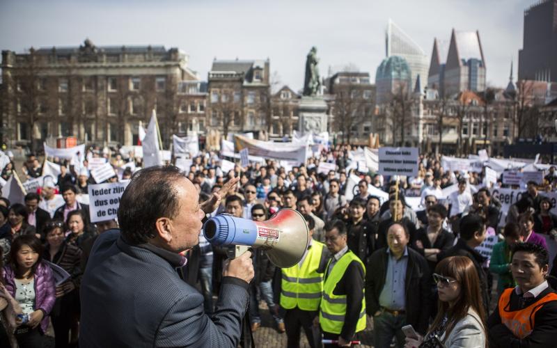 Man met megafoon praat tegen menigte tijdens demonstratie in Den Haag