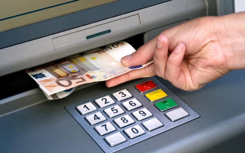 Een hand haalt een briefje van 50 euro uit een pinautomaat