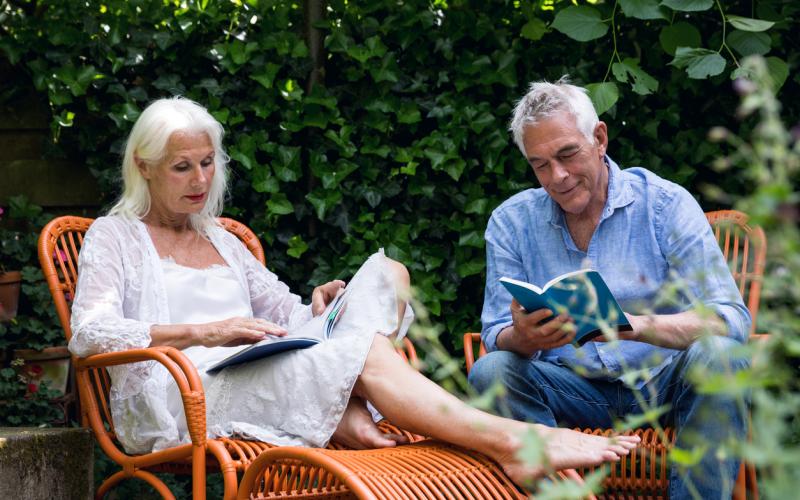 Gepensioneerd echtpaar lezend in de tuin Gepensioneerd echtpaar lezend in de tuin