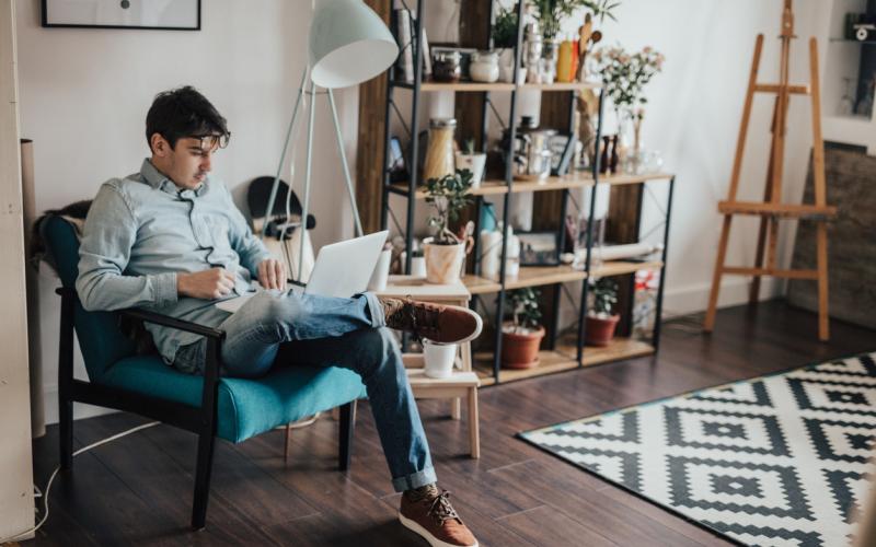 Jongen in huiskamer met laptop op schoot