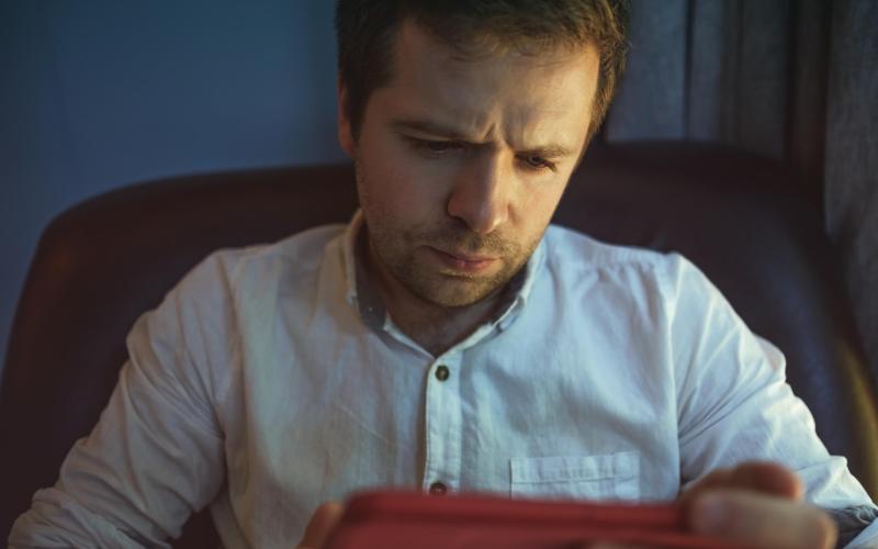 Man kijkt fronsend naar tablet in zijn handen