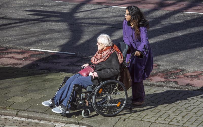 Vrouw in rolstoel wordt rondgereden Vrouw in rolstoel wordt rondgereden