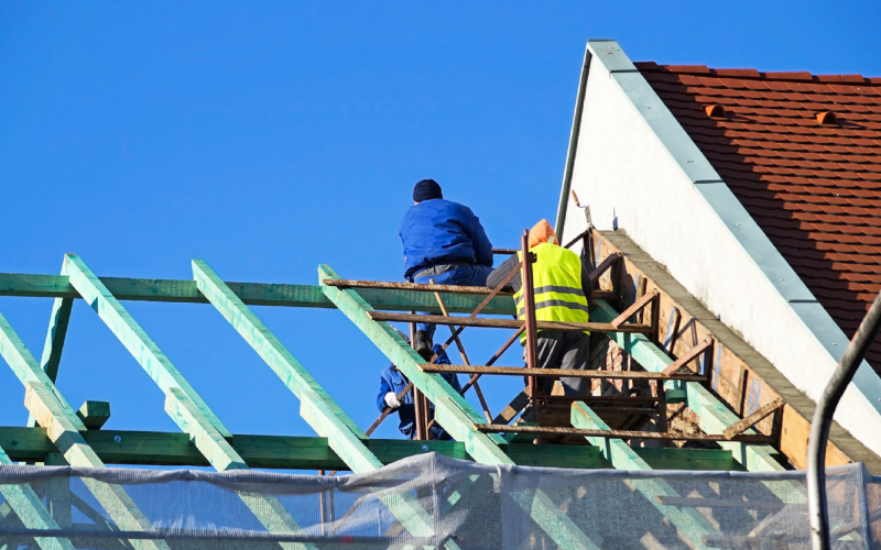 Twee mannen aan het werk met een aanbouw Twee mannen aan het werk met een aanbouw