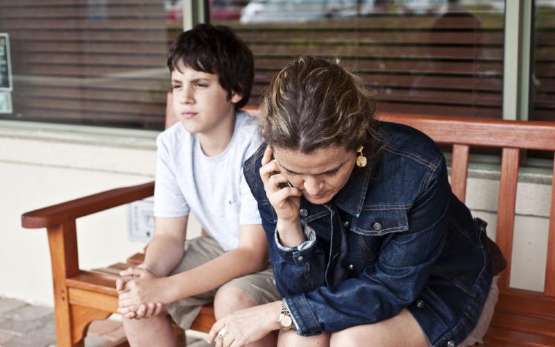 Vrouw en zoon zitten op een bankje te bellen Vrouw en zoon zitten op een bankje te bellen