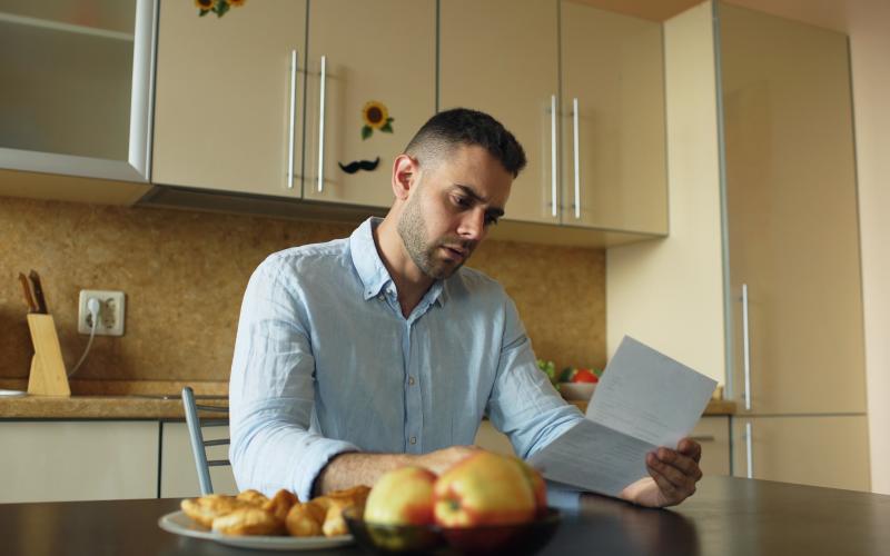 Man leest brief in de keuken