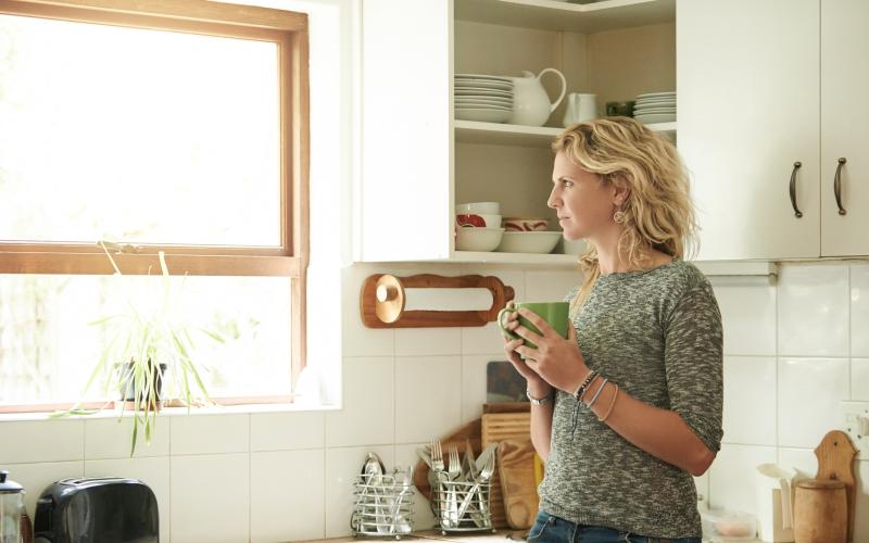 Vrouw in de keuken met een kop koffie Vrouw in de keuken met een kop koffie