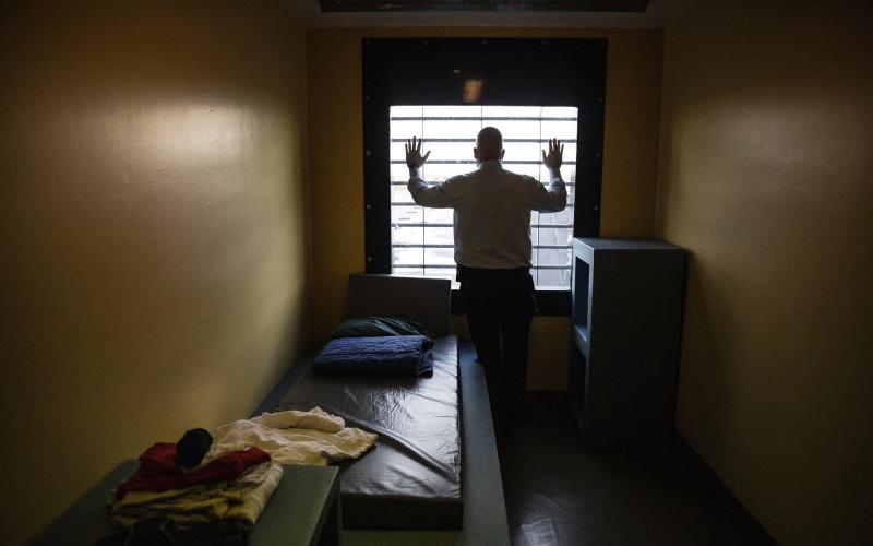 Man in gevangenis staat voor het raam Man in gevangenis staat voor het raam