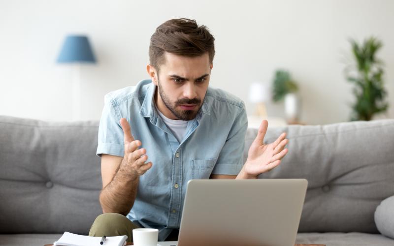 Man kjikt verbaasd naar zijn laptop