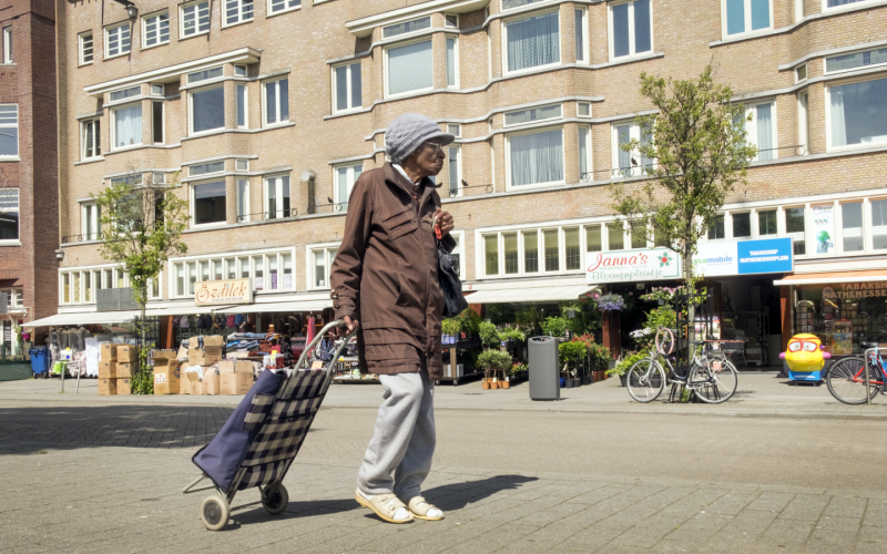 oudere dame met boodschappenkar loopt over straat
