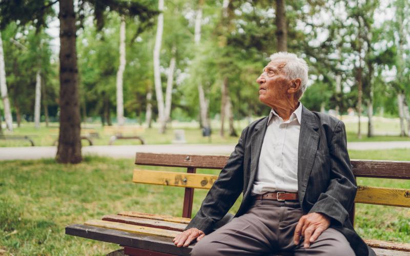 Foto van een senior man op een bankje in het park