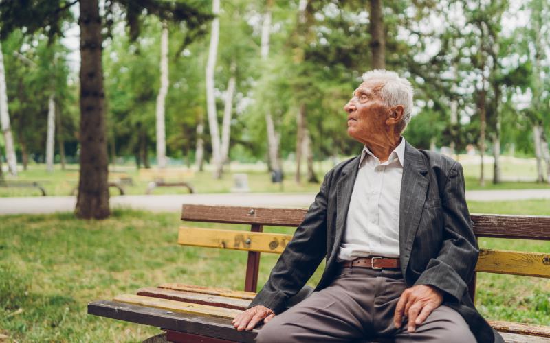 Foto van een senior man op een bankje in het park