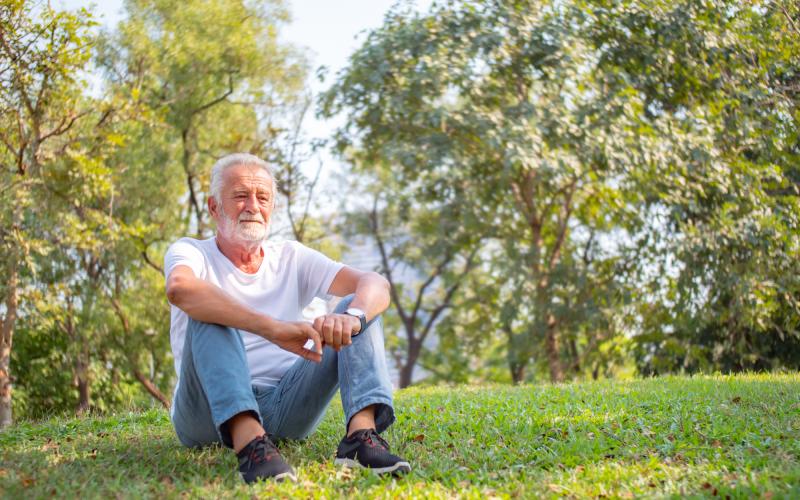 Foto van een senior man zitten op een grasveld