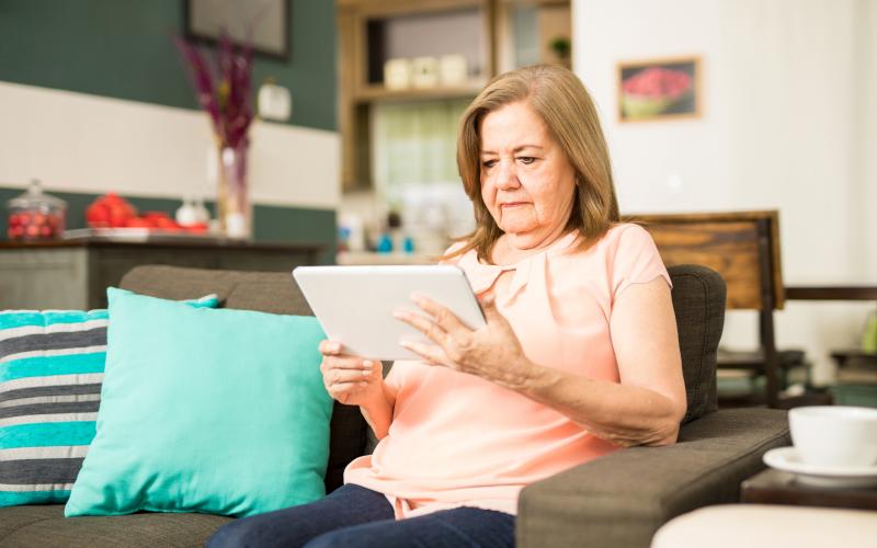 Senior vrouw met een tablet op de bank Senior vrouw met een tablet op de bank