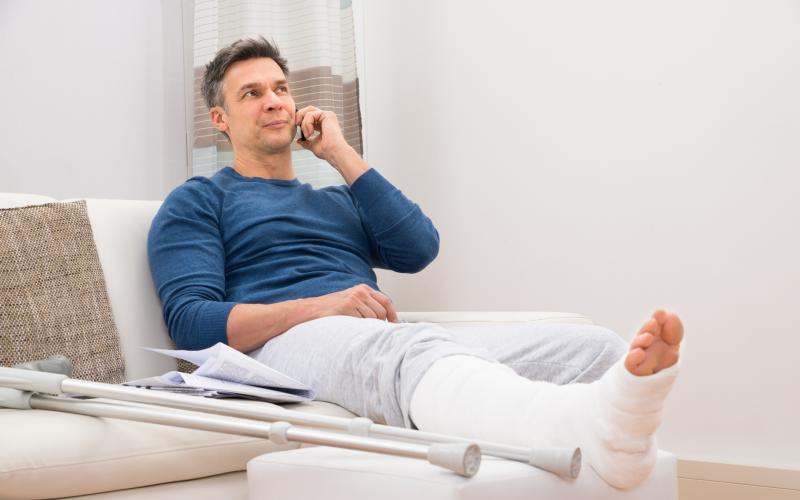 Man met been in het gips aan de telefoon