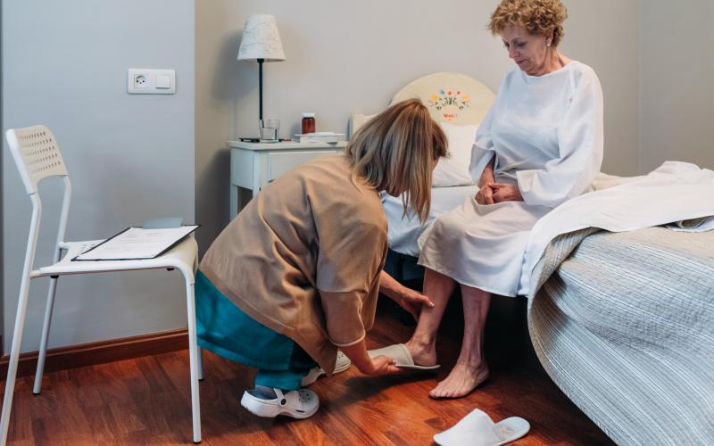 Verzorger helpt oudere vrouw met aankleden Verzorger helpt oudere vrouw met aankleden