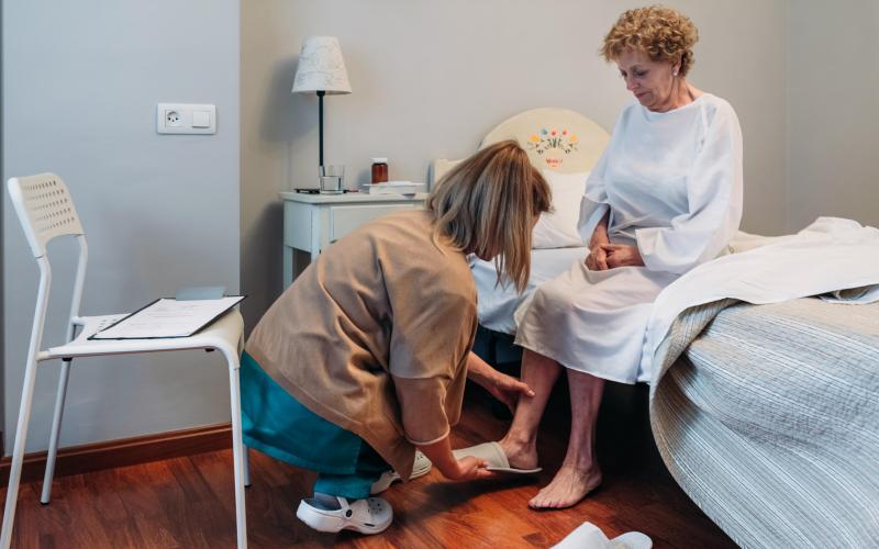 Verzorger en oudere dame aan bed Verzorger en oudere dame aan bed