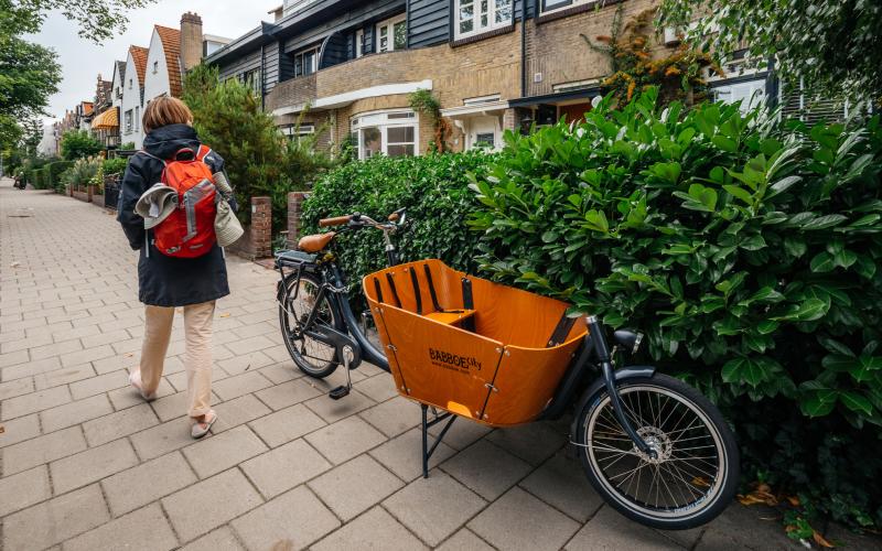 Vrouw loopt langs bakfiets Vrouw loopt langs bakfiets