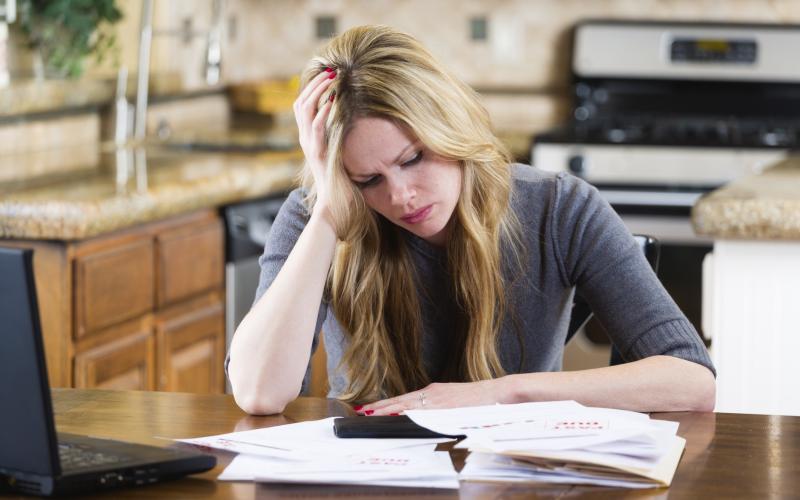 Vrouw met een stapel brieven aan de keukentafel