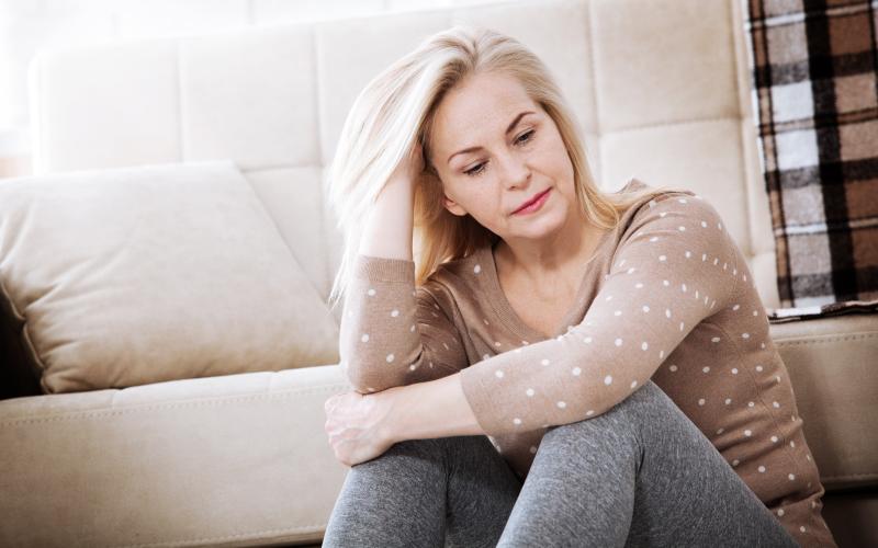 Vrouw met blond haar kijkt al zittend op de grond bezorgd voor zich uit