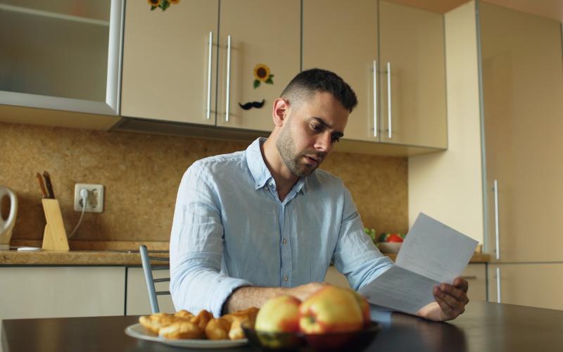 Man leest brief aan tafel in keuken