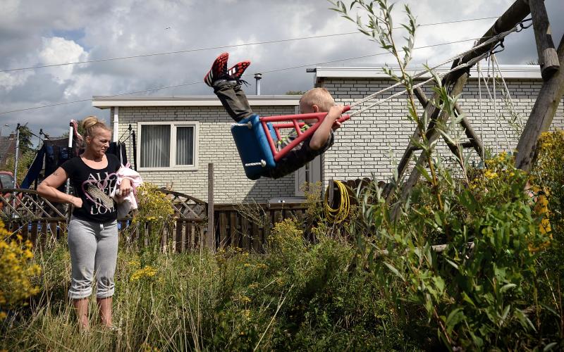 vrouw kijkt naar schommelend kind in tuin vrouw kijkt naar schommelend kind in tuin