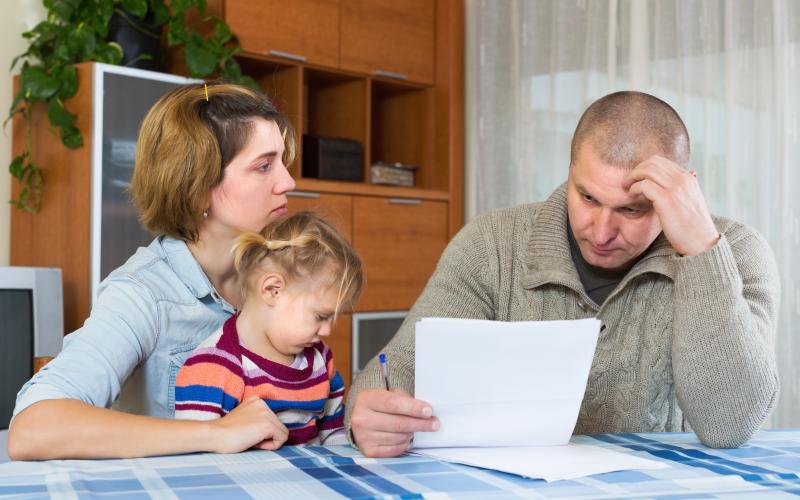 man leest brief aan tafel met vrouw en kind