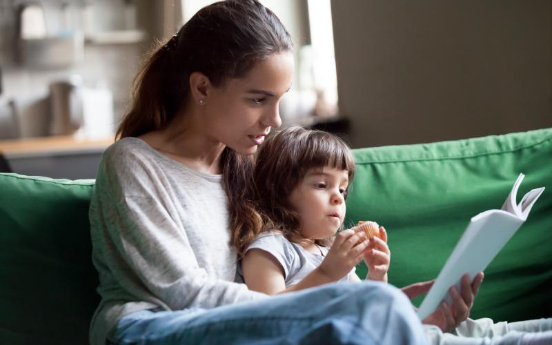 Moeder met kind op de bank lezen in een folder Moeder met kind op de bank lezen in een folder
