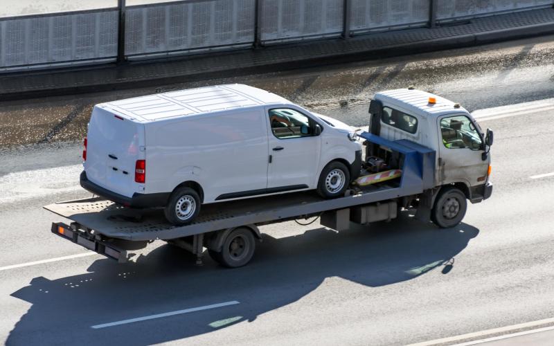 Een witte bestelbus die wordt weggesleept op een vrachtwagen