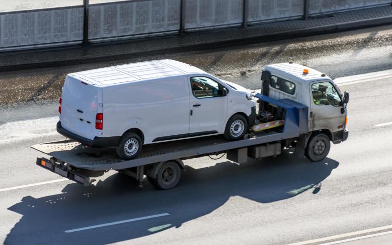 Een witte bestelbus die wordt weggesleept op een vrachtwagen Een witte bestelbus die wordt weggesleept op een vrachtwagen