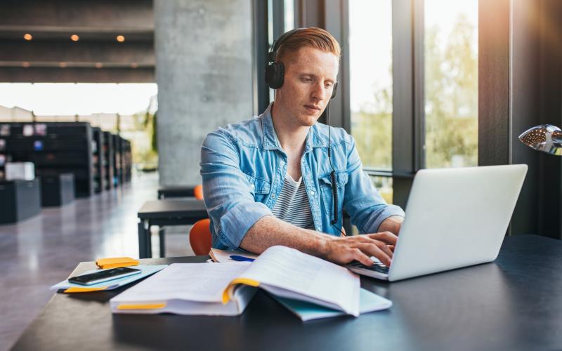 Student in bibliotheek werkt op laptop met twee-factor-authenticatie