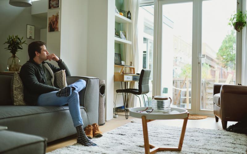 Man zit thuis op de bank in zijn woonkamer Man zit thuis op de bank in zijn woonkamer