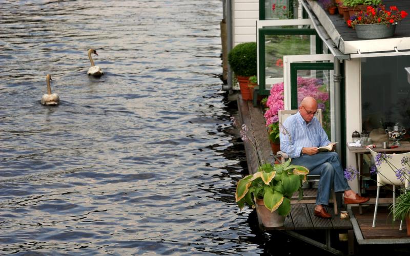 lezende man op terras van woonboot bij artikel over pensioen