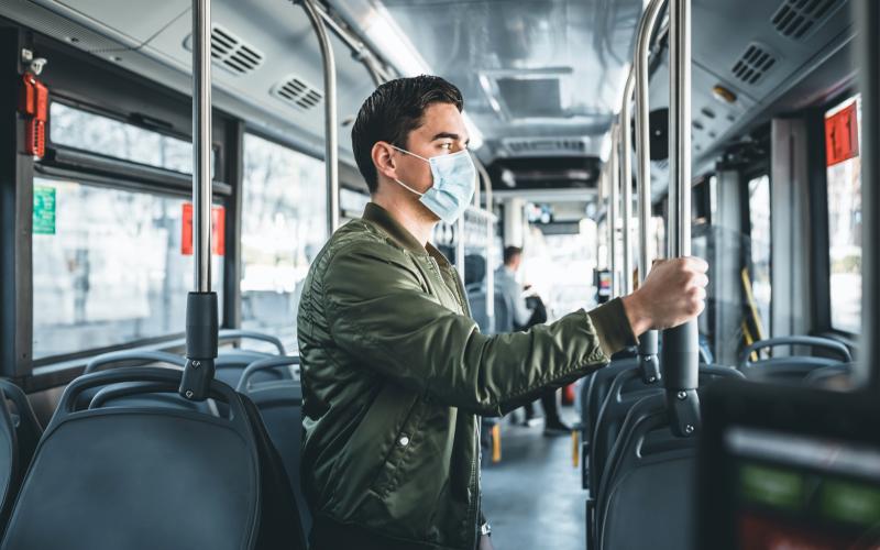 Een jonge man met een mondkapje staat in de tram